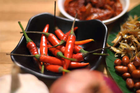 Nasi lemak is served with a hot spicy sauce, cucumber slices, small fried anchovies, roasted...