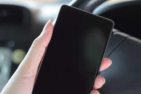 Mobile smart phone with blank screen in car. Smartphones make driving easier.の写真素材