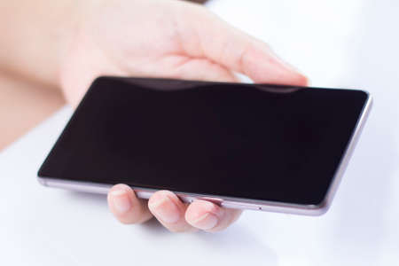 Hand holding mobile smartphone with blank screen. A smartphone is a mobile or cellular phone that...