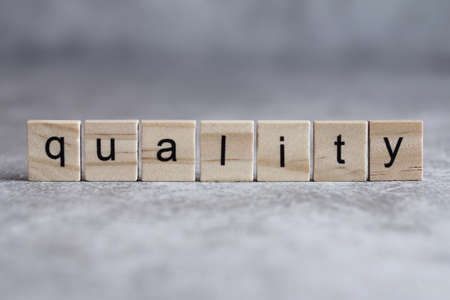 Quality word written on wood cube with gray background.の写真素材