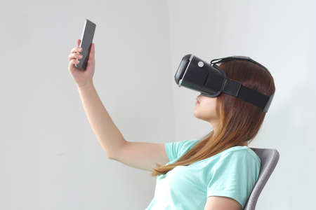 Young woman wearing virtual reality glasses at home. A virtual reality headset is a head-mounted...