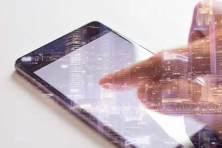 Business technology concept, double exposure image of hand using smartphone with cityscape backgroundの写真素材