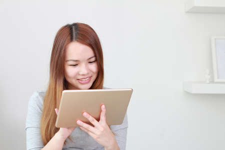 Young woman using tablet at home. A tablet is a wireless touch screen personal computer that is smaller than a notebook but larger than a smartphone.の写真素材