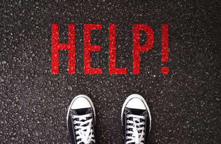 Black shoes standing at the road with help wording.の写真素材