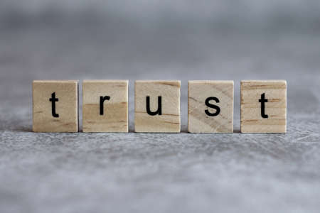 Trust word written on wood cube with gray background.の写真素材