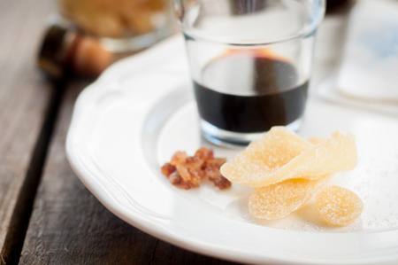 Herbal Liqueur with Crystallized Ginger and Brown Rock Sugar on a White Plate, copy space for your textの写真素材