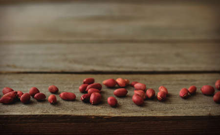 Peanuts scattered over wooden surface; good as a background or texture