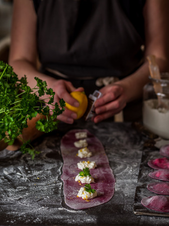 Female Making Beet Ravioli with Cottage Cheese, Lemon Zest and Parsley, copy space for your textの写真素材