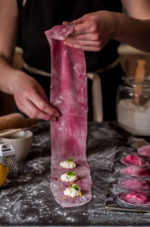 Female Making Beet Ravioli with Cottage Cheese, Lemon Zest and Parsley, copy space for your textの写真素材