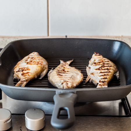 Grilling Breams in a Skillet on Gas Stove Topの写真素材