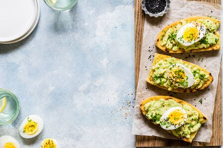 Mashed Avocado and Boiled Egg Toasts with Chives and Black Sesame Seeds, copy space for your textの写真素材