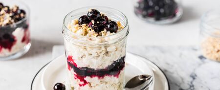 Layered Creamy Oat Porridge in a Jar with Blackcurrants and Chopped Almonds, bannerの写真素材