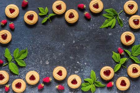Shortbread Butter Cookies with Raspberry Jam Filling Center, Fresh Berries and Leaves, Blue Concrete Background, copy space for textの写真素材