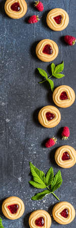 Shortbread Butter Cookies with Raspberry Jam Filling Center, Fresh Berries and Leaves, Blue Concrete Background, banner, copy space for your textの写真素材