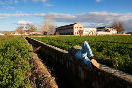 Man lying down and sleeping relaxed in a ditch wall.の写真素材