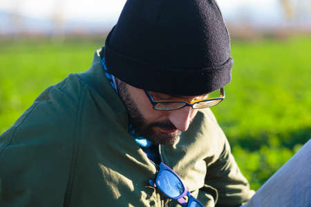Close-up portrait of a young adult man looking down in a meadow.の写真素材