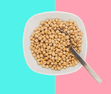 Uncooked raw chickpeas in a plate with spoon in paltel backgroundの写真素材