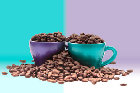 Cups of coffee filled with grain in a heap of beans in pastel colors backgroundの写真素材