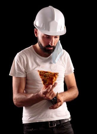 Young hispanic male construction worker trying to eat pizzaの写真素材
