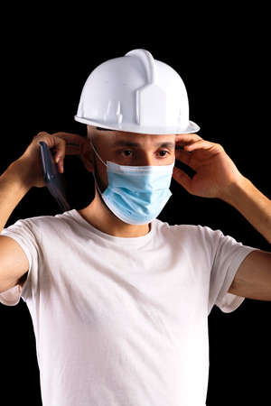 Young hispanic male construction worker putting on a maskの写真素材