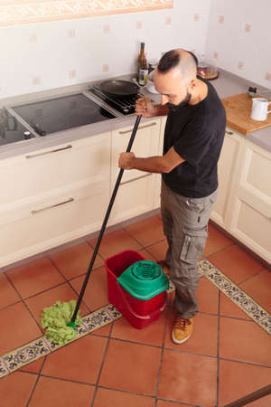 High angle view of a young hispanic self-sufficient man mopping the floor
