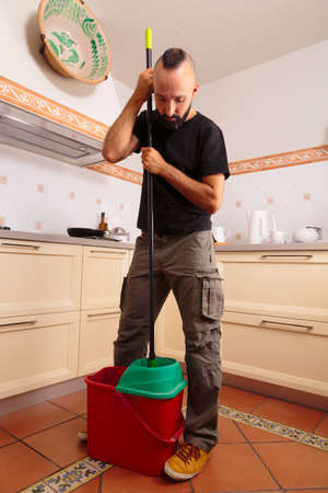 Self-sufficient young hispanic man squeezing the mopの写真素材