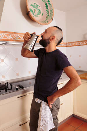 Young hispanic self-sufficient man drinking directly from the coffee potの写真素材