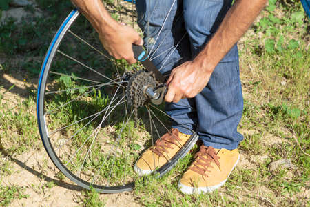 Young man adjusting a bikes wheel in the backyardの写真素材