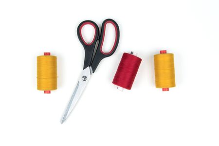 Colored sewing thread coils with scissors on white background