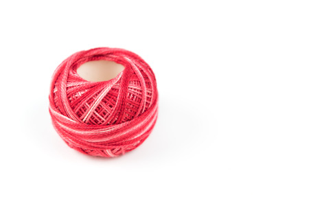 One red sewing thread on a white background