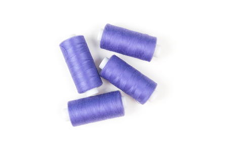 Four purple sewing threads on white background