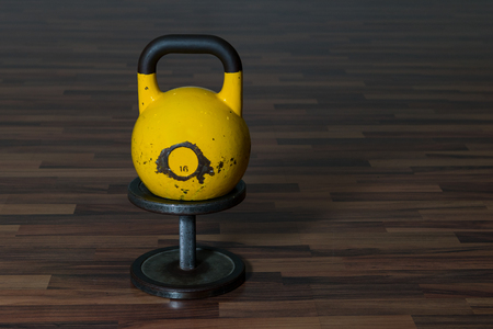 Big yellow kettlebell on a black dumbbell on a wooden floor. Workout equipmentの写真素材
