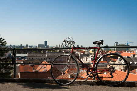 Vintage red city bicycle locked to the metal fence with view over Zagreb. Old red road bicycle.の写真素材