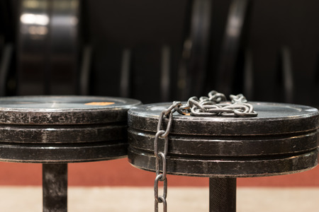 Two old and used gym black metal dumbbells with silver chain. Gym equipmentの写真素材