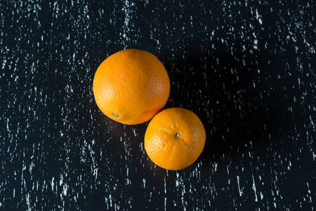 Two whole oranges on black wooden kitchen tableの写真素材