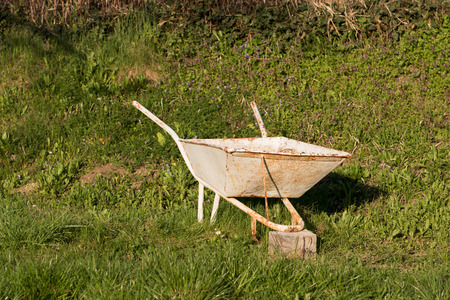 Old vintage wheelbarrow on a green grass in a gardenの写真素材