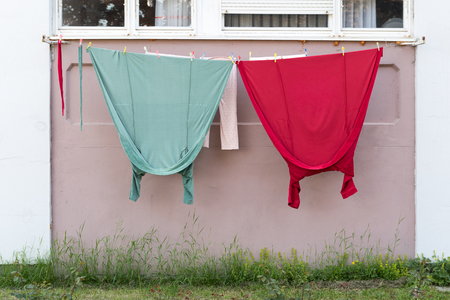 Dried laundry hanging on line. Red and green clothesの写真素材