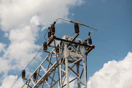 Train or railway power line support. Railway power lines with high voltage electricity on metal poles against blue sky.の写真素材