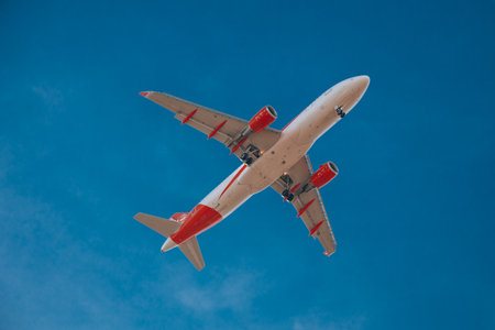 White-red airplane in the sky, bottom view. Airplane landingのeditorial素材