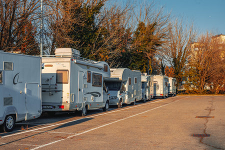 Milan, Italy 28.11.2023 Many white modern campervan recreational motor home vehicles parked in row at camper park site Milan city. Motorhome campground stataion travel destination.のeditorial素材