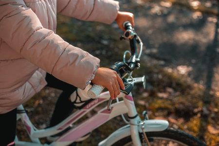 Portrait of a cute girl riding a bicycle against yellow leaves background. Funny kid riding bike outdoor in autumn park in the backlight. Autumn park in November. Full frame side view. Italy, Milanの写真素材