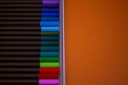 Set of colorful pencils on orange background, top view. Set of colored pencils arranged evenly on an orange background. Colored pencils are arranged exactly in a row.の写真素材