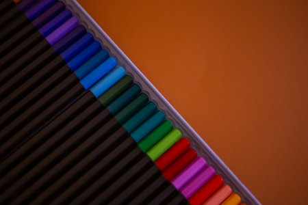 Set of colorful pencils on orange background, top view. Set of colored pencils arranged evenly on an orange background. Colored pencils are arranged exactly in a row.の写真素材
