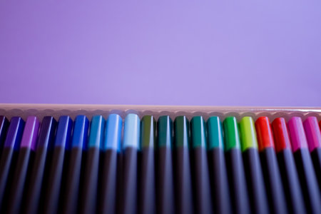 Learn from home concept. Drawing and art education. Set of colorful pencils on violet background, top view. Set of colored pencils arranged evenly on an violet background. Colored pencils are arrangedの写真素材