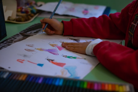 Little girl draws at home, creativity development. POV child painting a picture with school supplies, preschool child painting, child doing homework.の写真素材