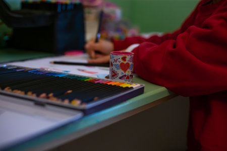 Little girl draws at home, creativity development. POV child painting a picture with school supplies, preschool child painting, child doing homework.の写真素材