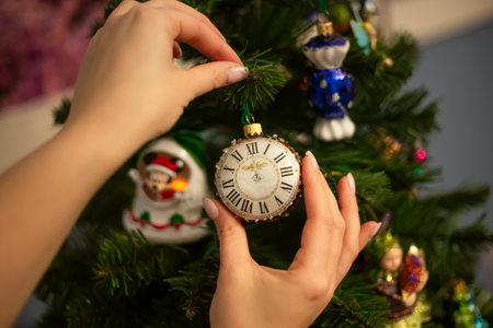 Hands decorating christmas tree with stylish bauble in atmospheric festive room. Merry Christmas. Winter holidays preparation.の写真素材