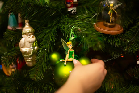 Hands decorating christmas tree with stylish bauble in atmospheric festive room. Merry Christmas. Winter holidays preparation.の写真素材