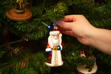 Decorating Christmas tree, close up, copy space. Merry Christmas and Happy New Year. Women hands decorate the Christmas tree with balls and toys.の写真素材