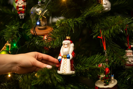 Decorating Christmas tree, close up, copy space. Merry Christmas and Happy New Year. Women hands decorate the Christmas tree with balls and toys.の写真素材